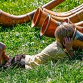 ein Junge liegt auf einer Wiese und blickt in das Ende eines Alphorns