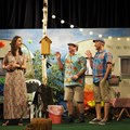 eine Frau und zwei Männer in Sommerkleidung vor Campingplatz-Kulisse